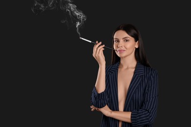 Woman using long cigarette holder for smoking on black background, space for text