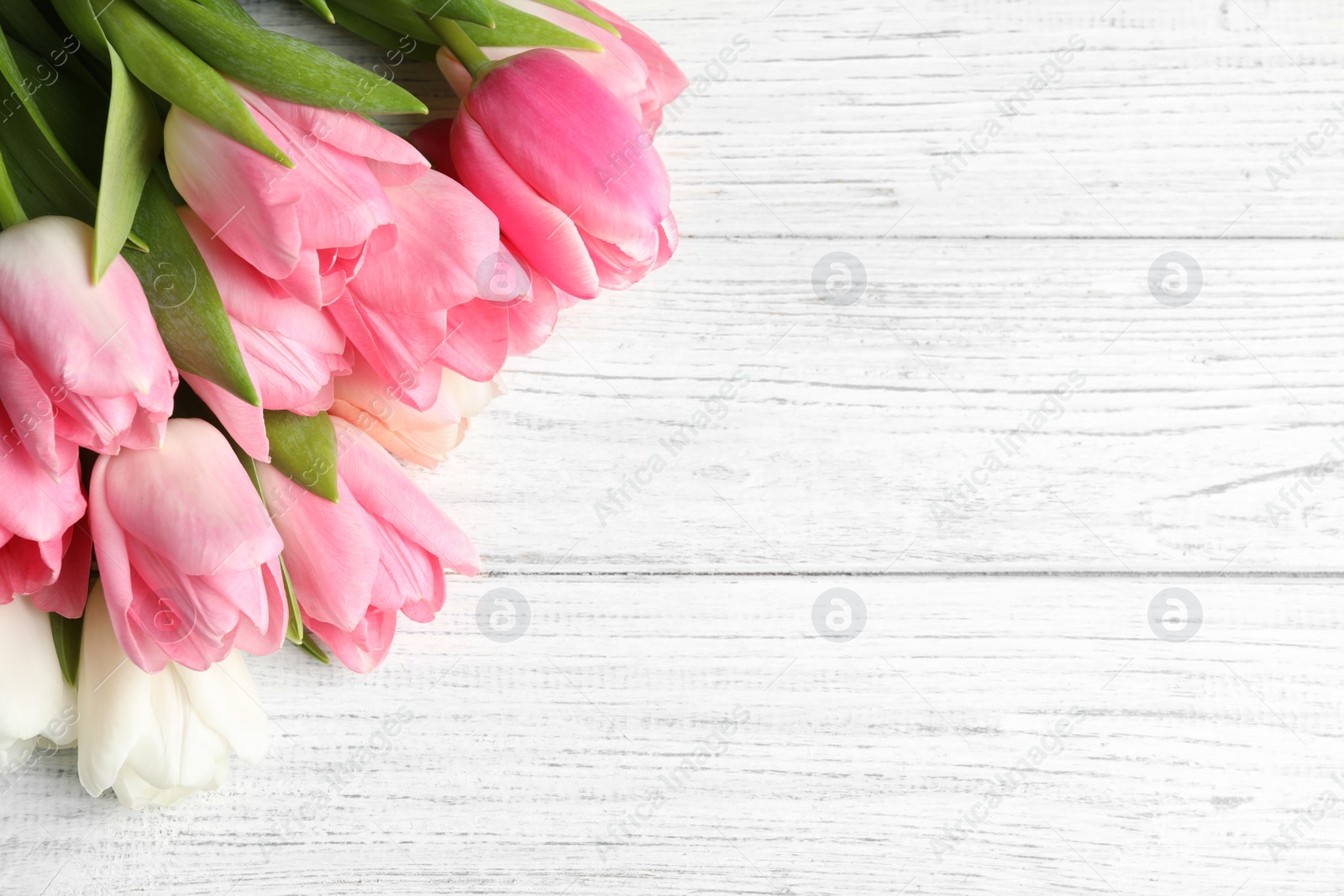 Photo of Beautiful spring tulips on wooden background, top view with space for text. International Women's Day