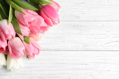 Photo of Beautiful spring tulips on wooden background, top view with space for text. International Women's Day