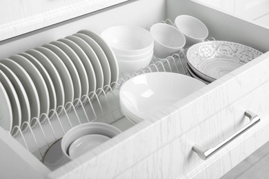 Open drawer with different plates and bowls in kitchen, closeup