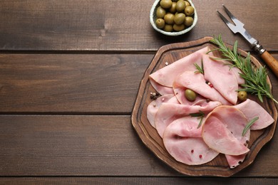 Photo of Slices of delicious ham with rosemary and olives served on wooden table, flat lay. Space for text