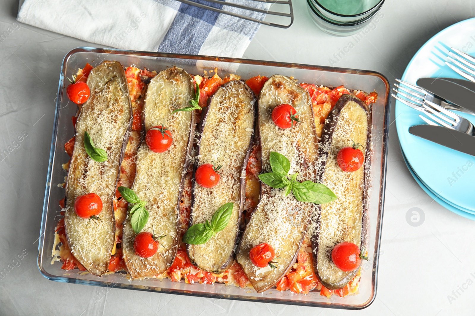 Photo of Flat lay composition with baked eggplant, tomatoes and basil in dishware on table