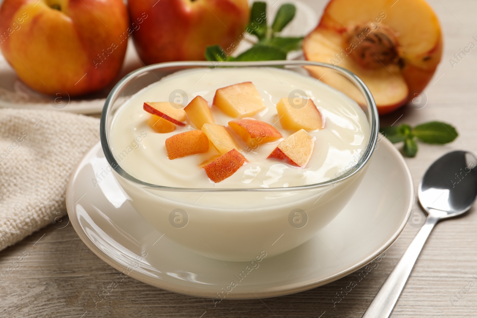 Photo of Delicious yogurt with fresh peach on light wooden table