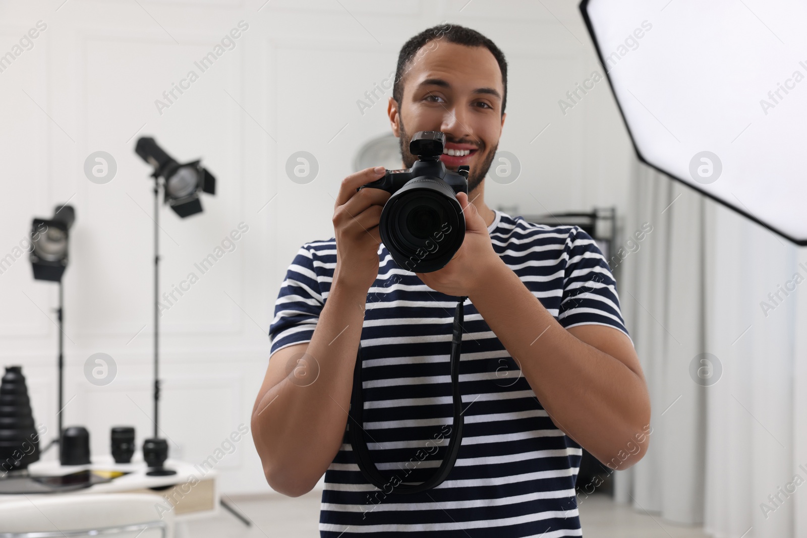 Photo of Young professional photographer with camera in modern photo studio, space for text