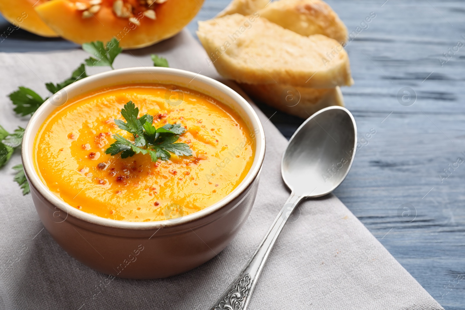 Photo of Delicious pumpkin cream soup in bowl on wooden background