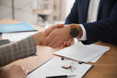 Photo of Real estate agent shaking hands with client in office, closeup