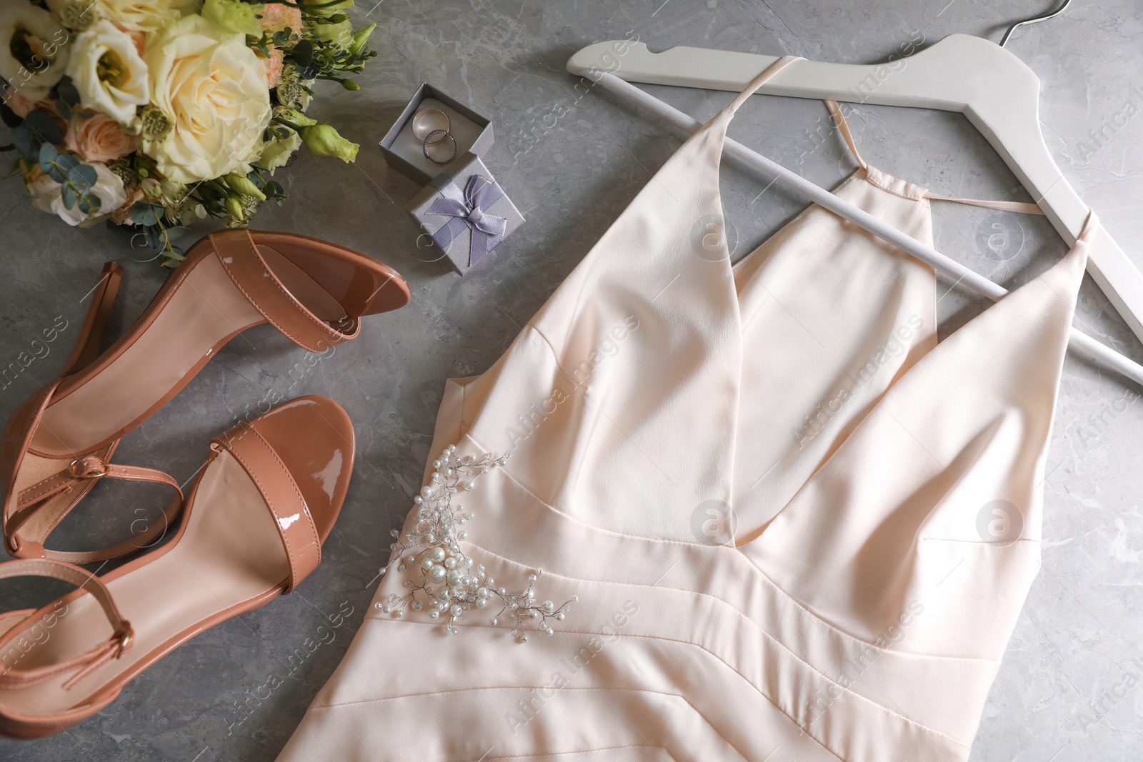 Photo of Flat lay composition with beige wedding dress and engagement rings on grey marble table