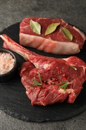 Photo of Pieces of raw beef meat and spices on grey textured table