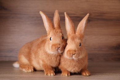 Photo of Cute bunnies on table against wooden background. Easter symbol