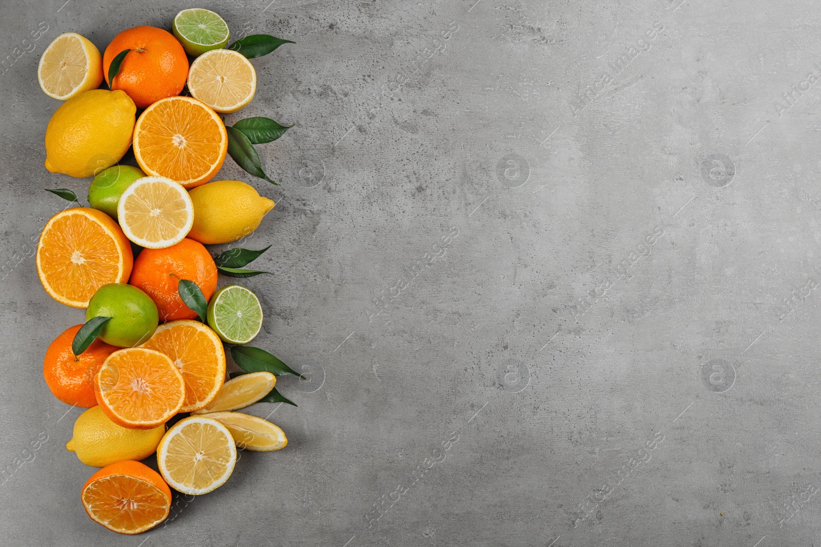 Photo of Flat lay composition with tangerines and different citrus fruits on grey background. Space for text