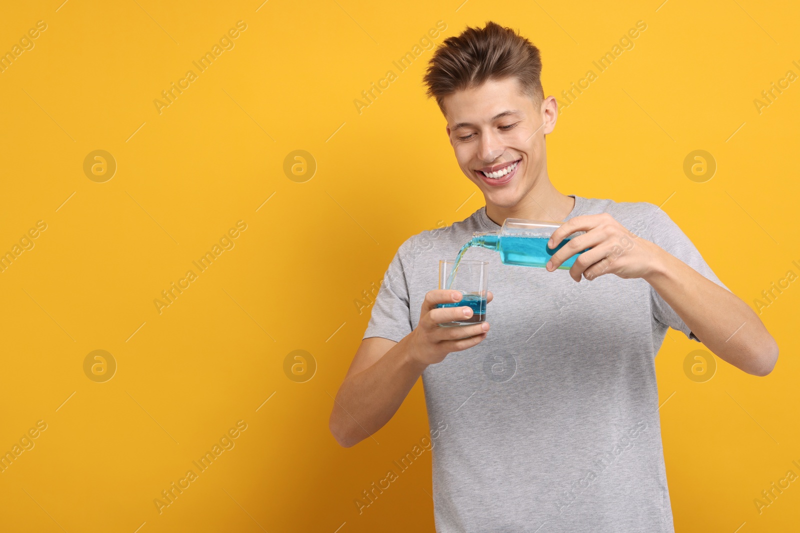 Photo of Young man using mouthwash on yellow background, space for text