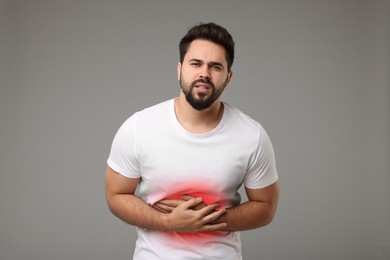 Man suffering from stomach pain on grey background