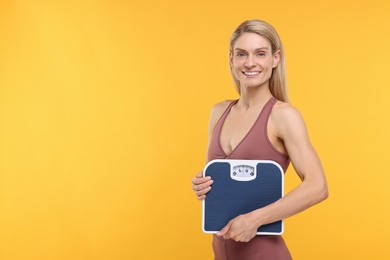 Photo of Slim woman holding scales on yellow background, space for text. Weight loss