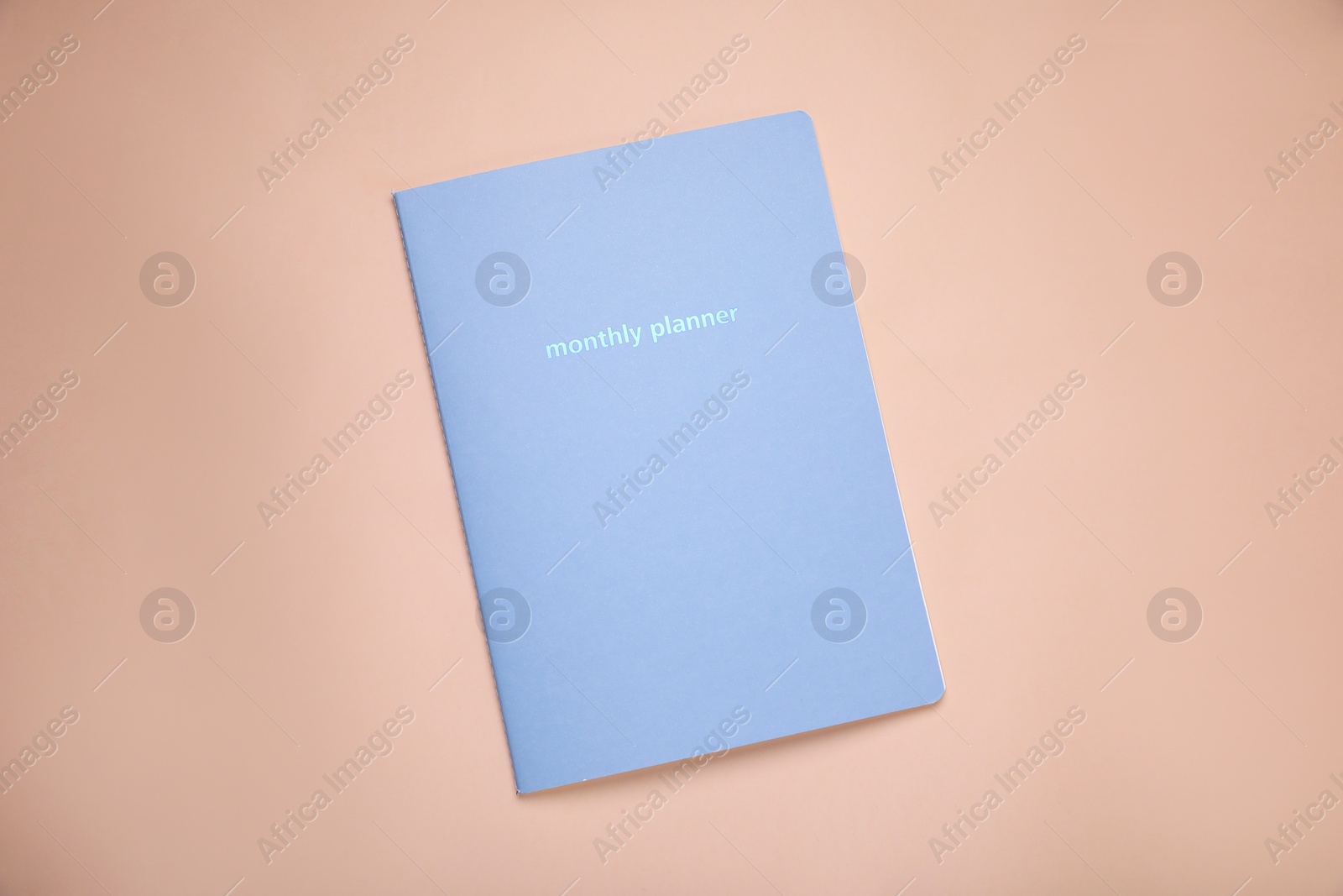 Photo of Monthly planner on beige background, top view