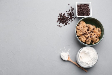 Photo of Flat lay composition with cookie dough, chocolate chips and flour on grey background