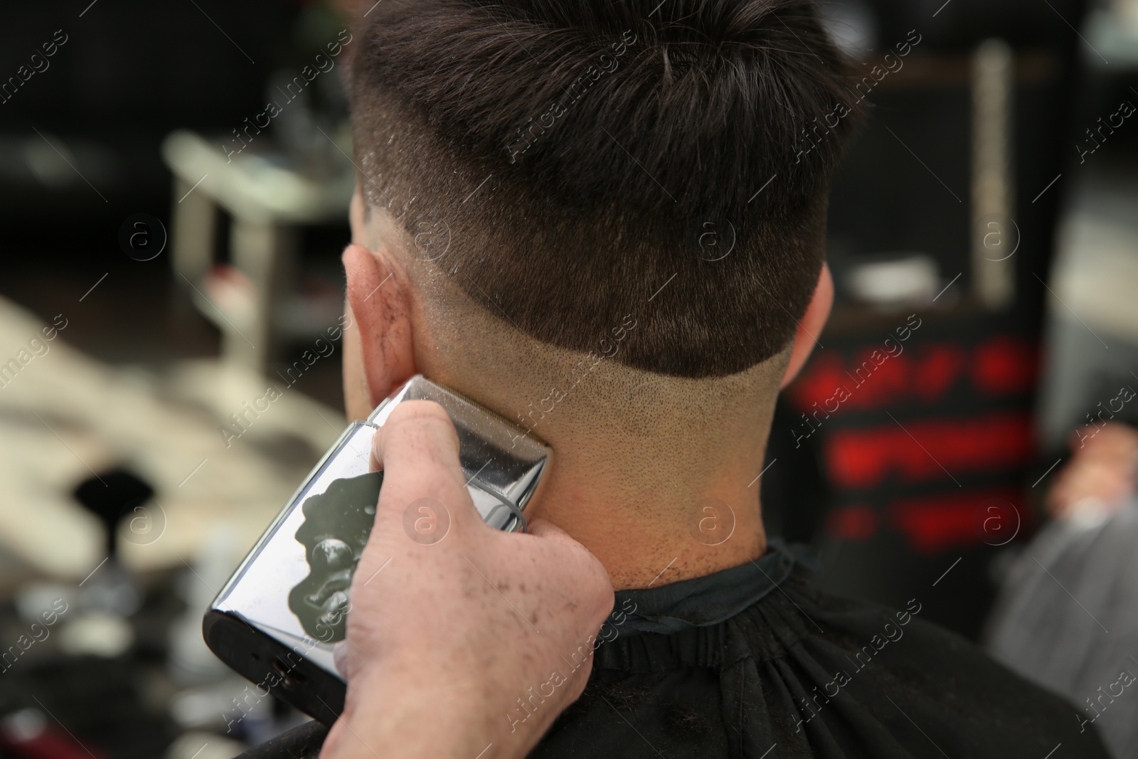 Photo of Professional barber making stylish haircut in salon, closeup