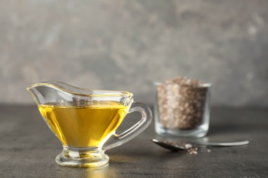 Photo of Sauce boat with chia seeds oil on grey table. Space for text