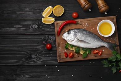 Photo of Flat lay composition with fresh raw dorado fish and spices on black wooden table. Space for text