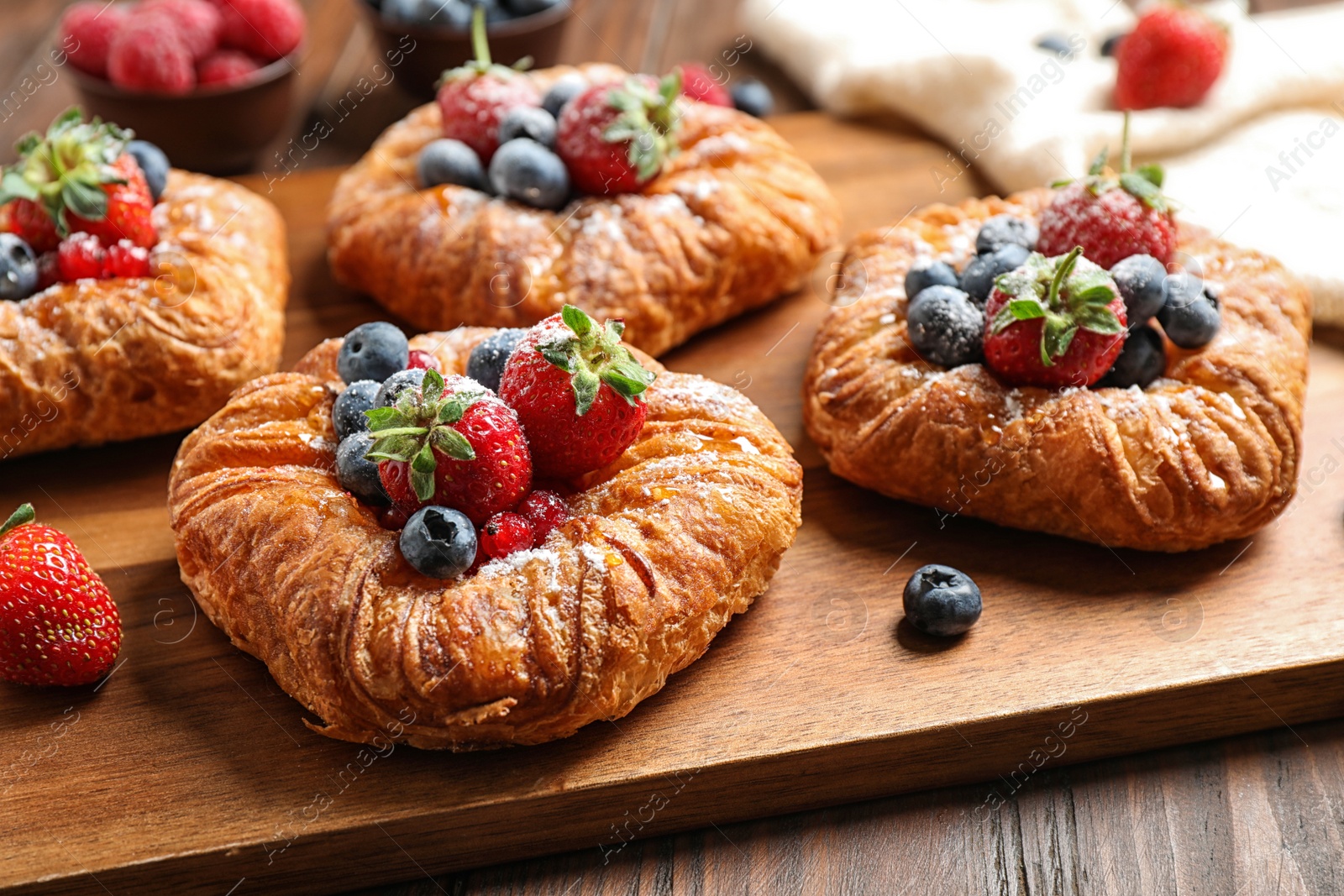 Photo of Fresh delicious puff pastry with sweet berries on wooden board, closeup