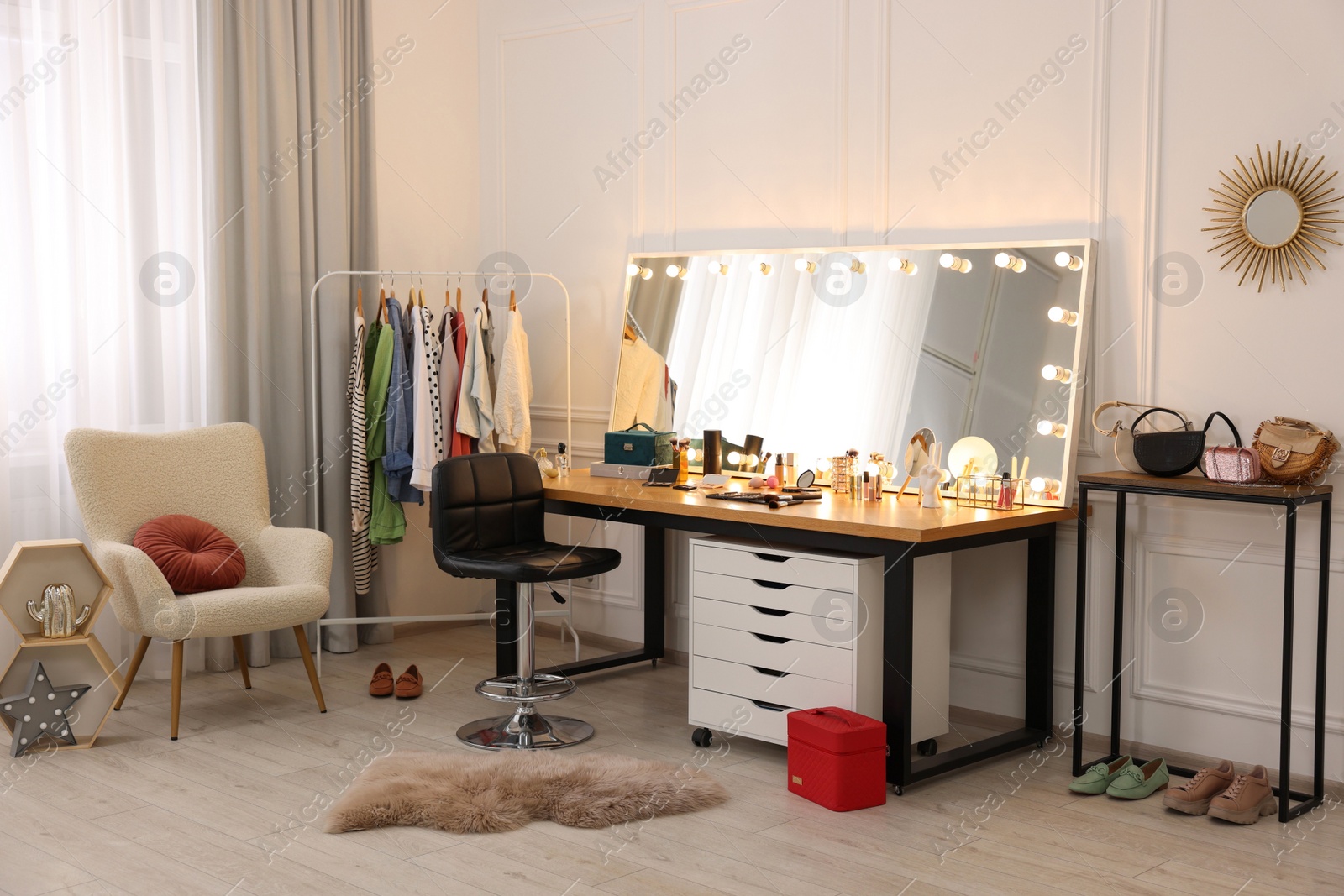 Photo of Makeup room. Stylish dressing table with mirror, chair and clothes rack