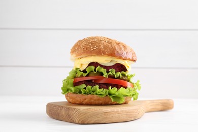 Photo of Delicious vegetarian burger on white wooden table