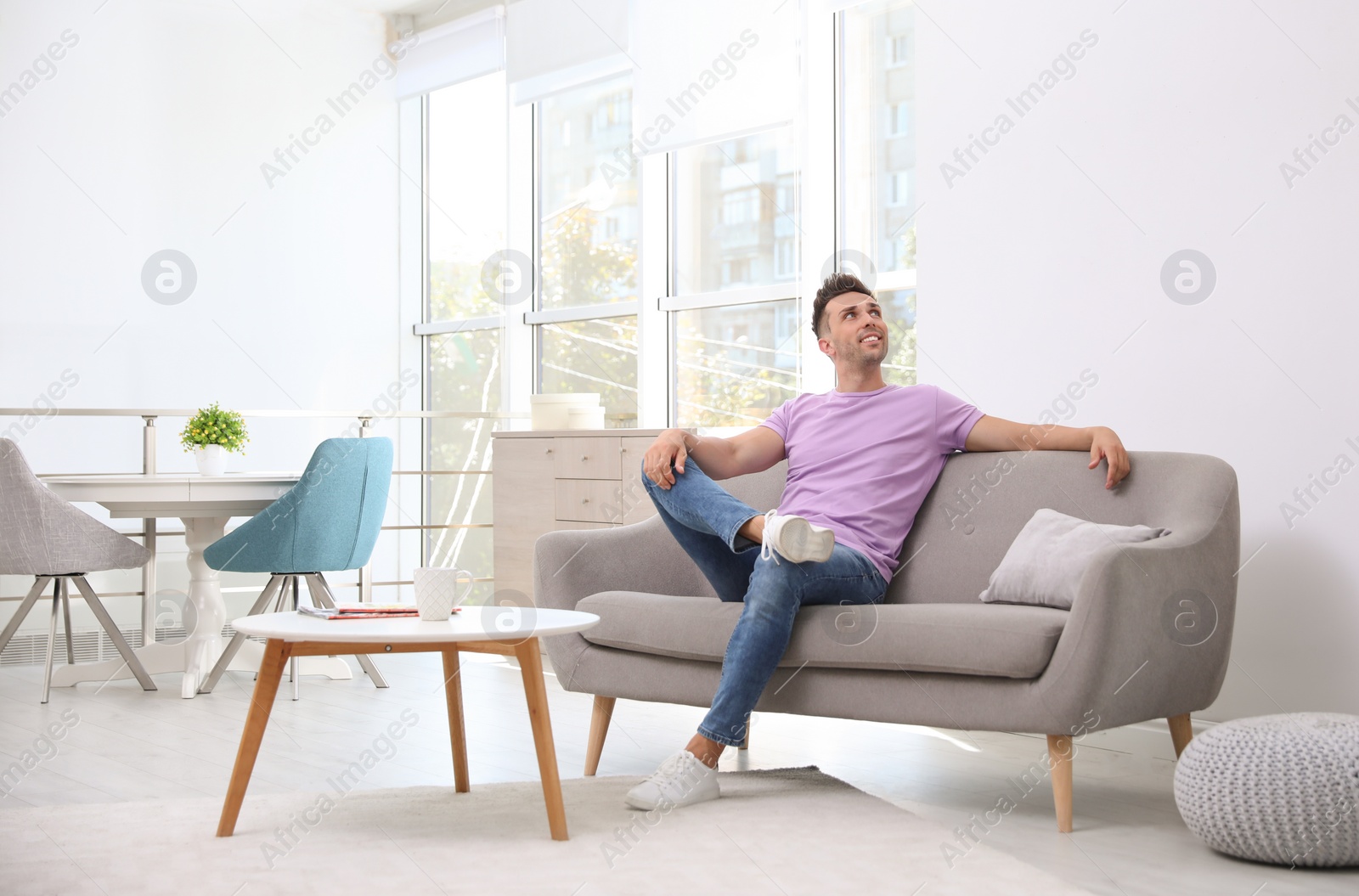 Photo of Young man relaxing on sofa under air conditioner at home