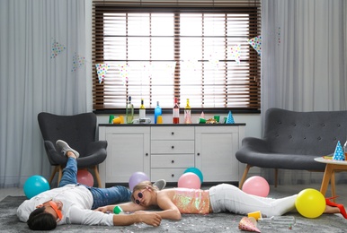 Photo of Drunk friends sleeping on floor in messy room after party