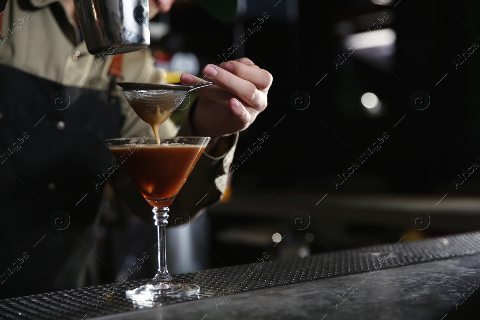 Photo of Barman pouring martini espresso cocktail into glass at counter, closeup. Space for text