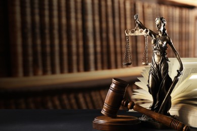 Law. Statue of Lady Justice, gavel and open book on black table indoors, space for text