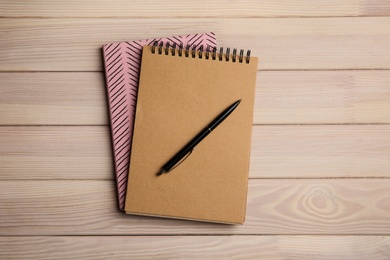 Photo of Notebooks and pen on wooden table, top view