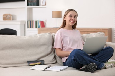 Online learning. Teenage girl with laptop on sofa at home