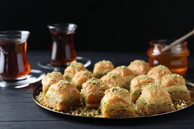 Photo of Delicious fresh baklava with chopped nuts on black wooden table. Eastern sweets