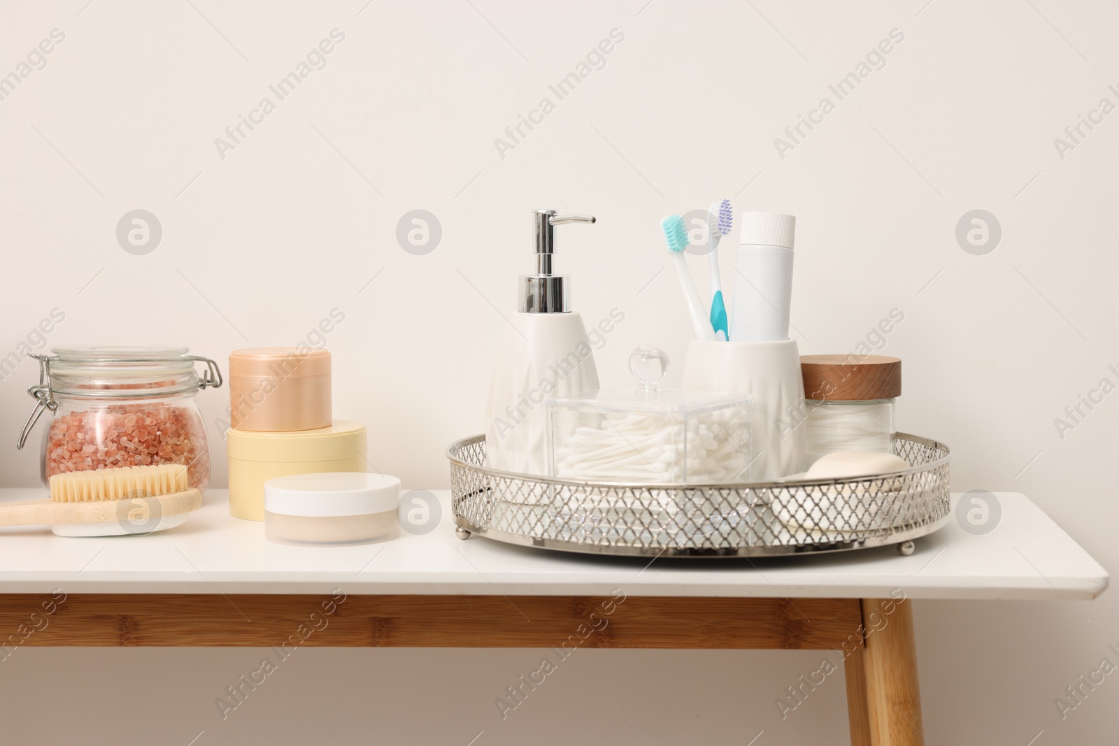 Photo of Different bath accessories and personal care products on table near white wall