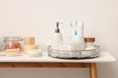 Different bath accessories and personal care products on table near white wall