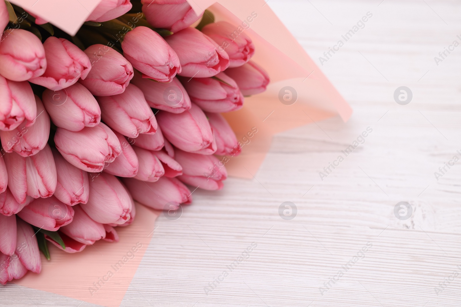 Photo of Bouquet of beautiful pink tulips on white wooden table, closeup. Space for text