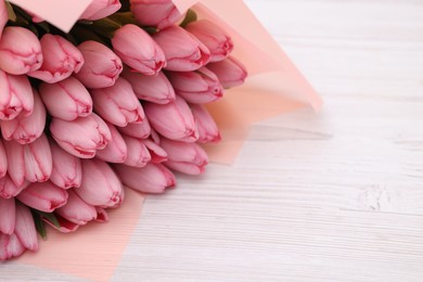 Bouquet of beautiful pink tulips on white wooden table, closeup. Space for text