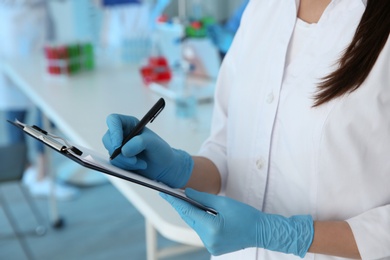 Photo of Medical student with clipboard working in scientific laboratory, closeup
