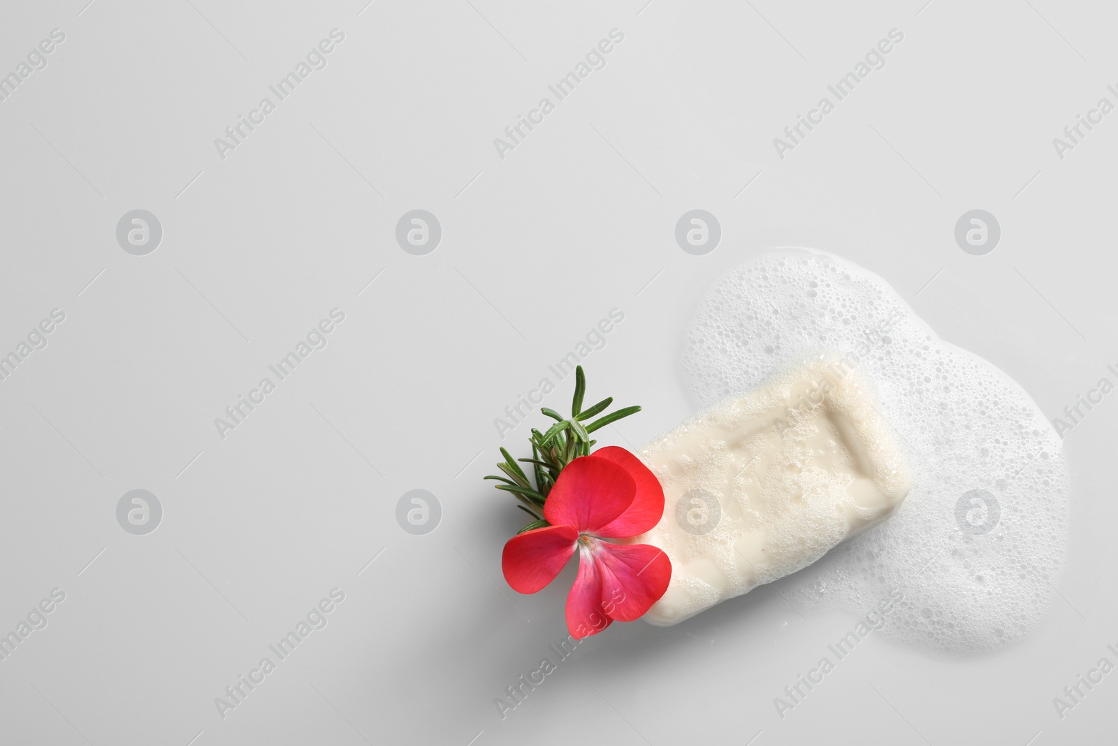 Photo of Soap bar, rosemary, flower and foam on white background, top view