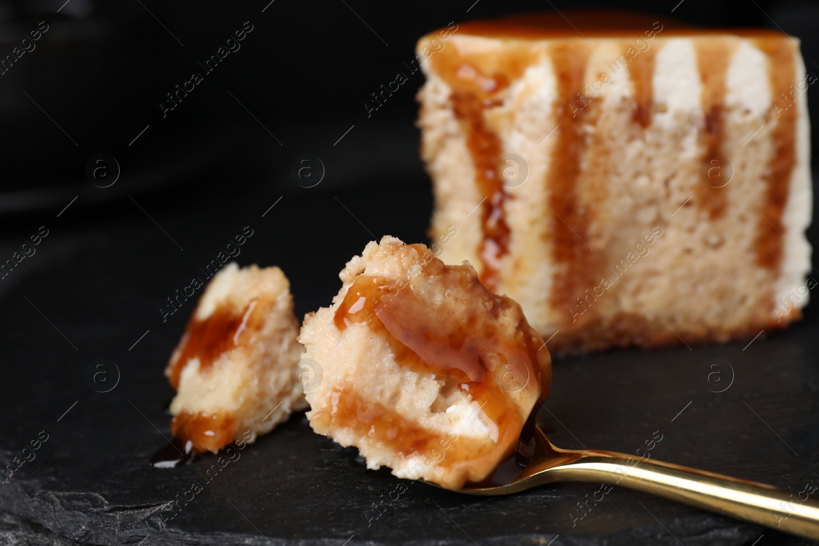 Photo of Slice of delicious cake with caramel sauce on slate board, closeup