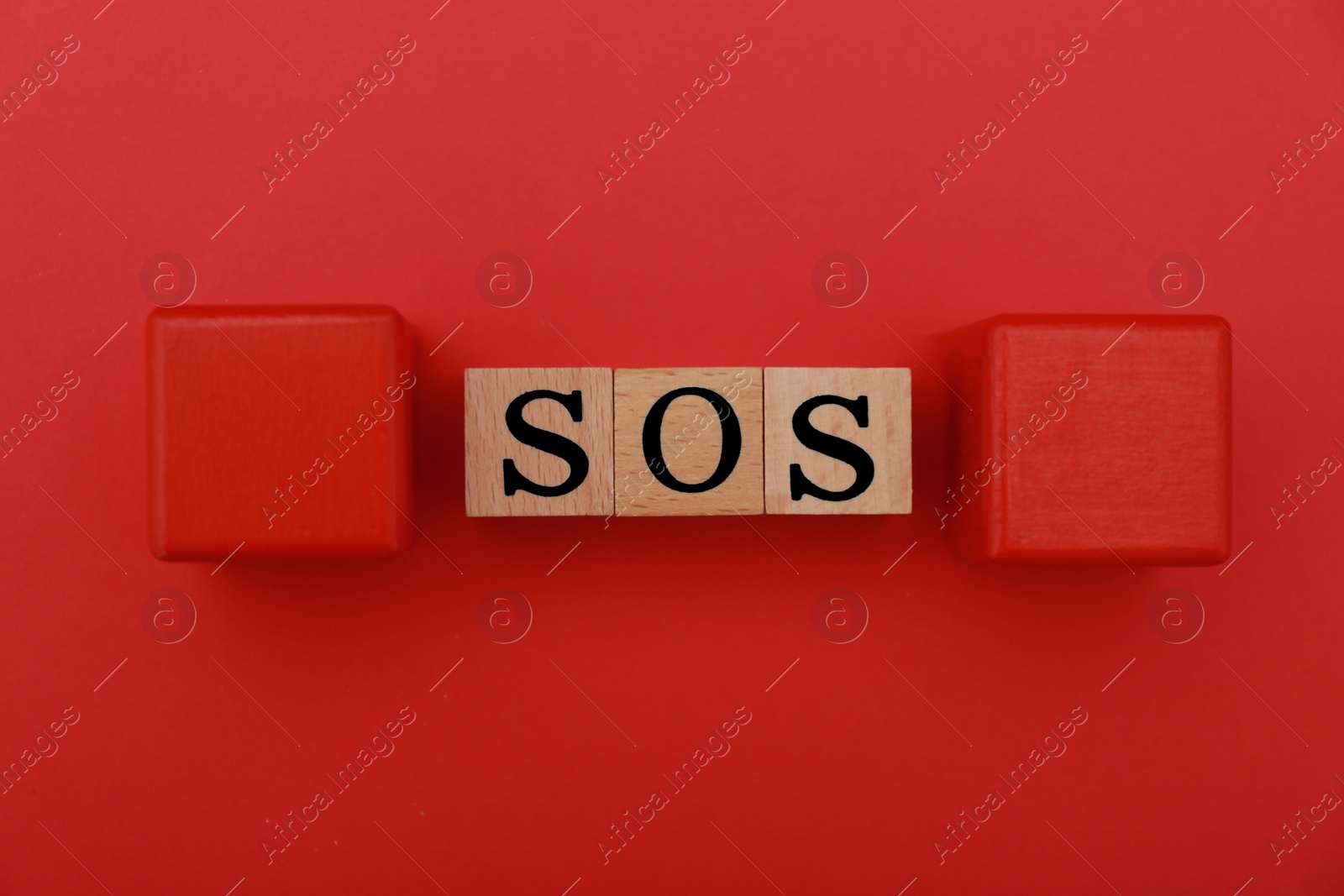 Photo of Abbreviation SOS made of wooden cubes on red background, flat lay