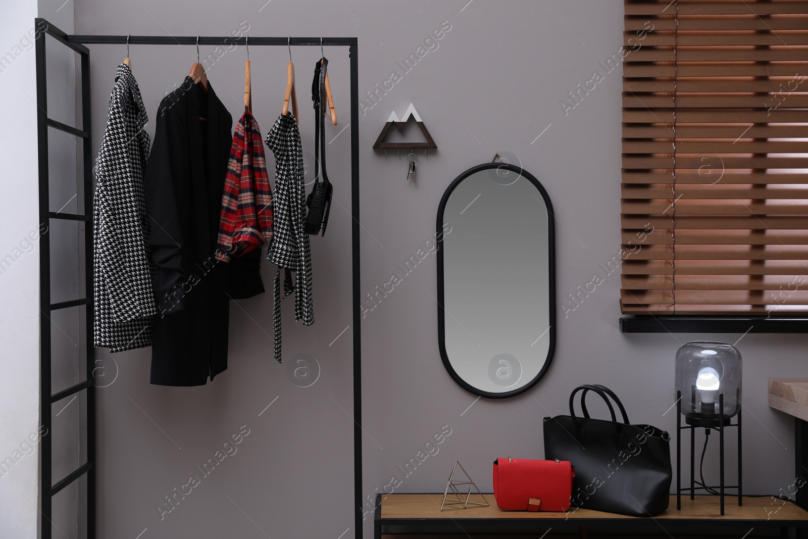 Photo of Modern hallway interior with stylish furniture, mirror and wooden hanger for keys on grey wall