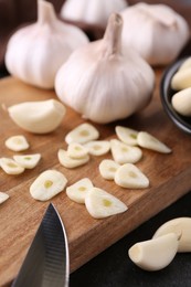 Aromatic cut garlic, cloves and bulbs on dark table, closeup