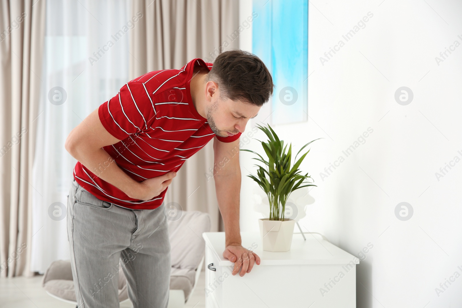 Photo of Young man having nausea at home. Space for text