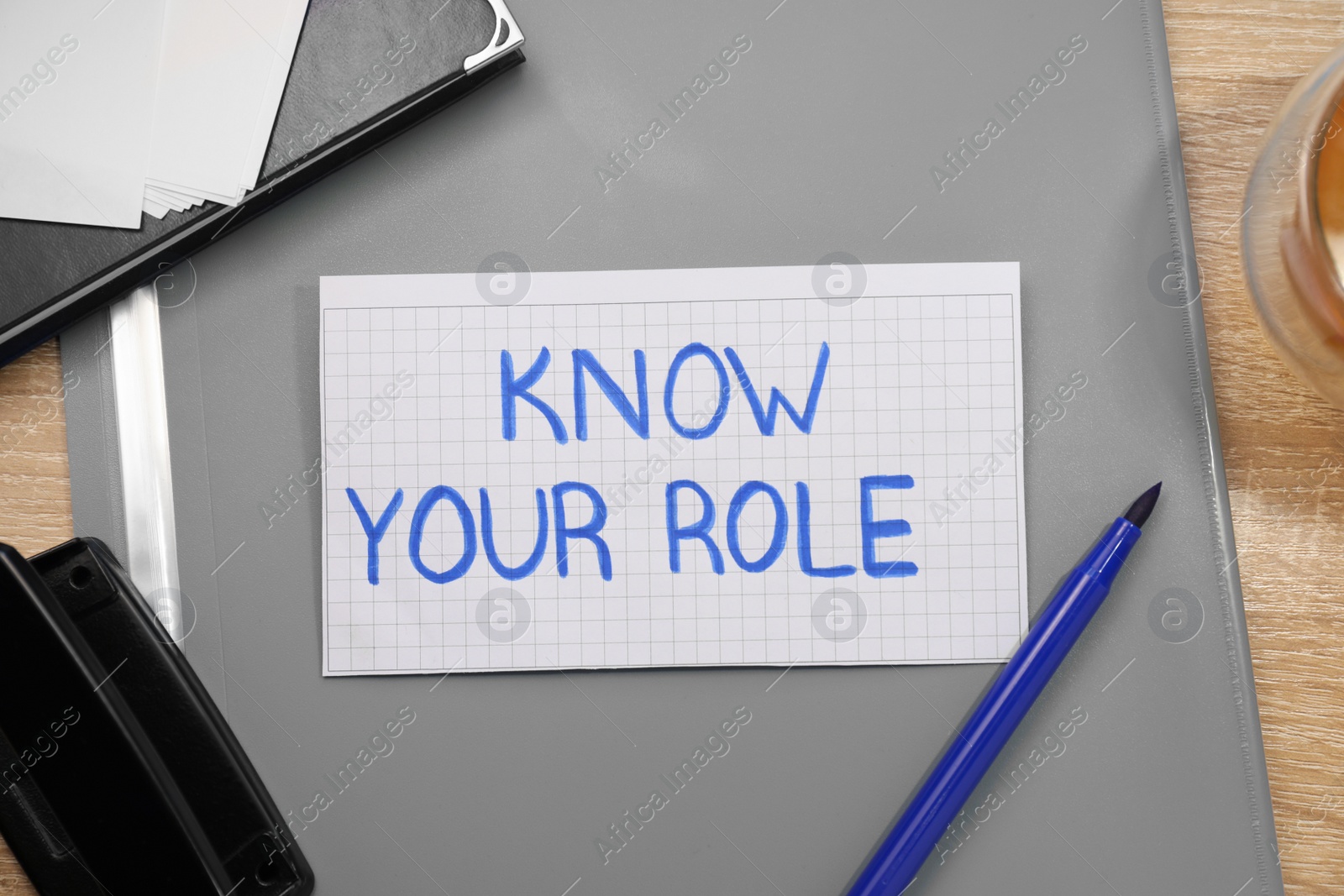Photo of Note with phrase Know Your Role and stationery on wooden table, flat lay