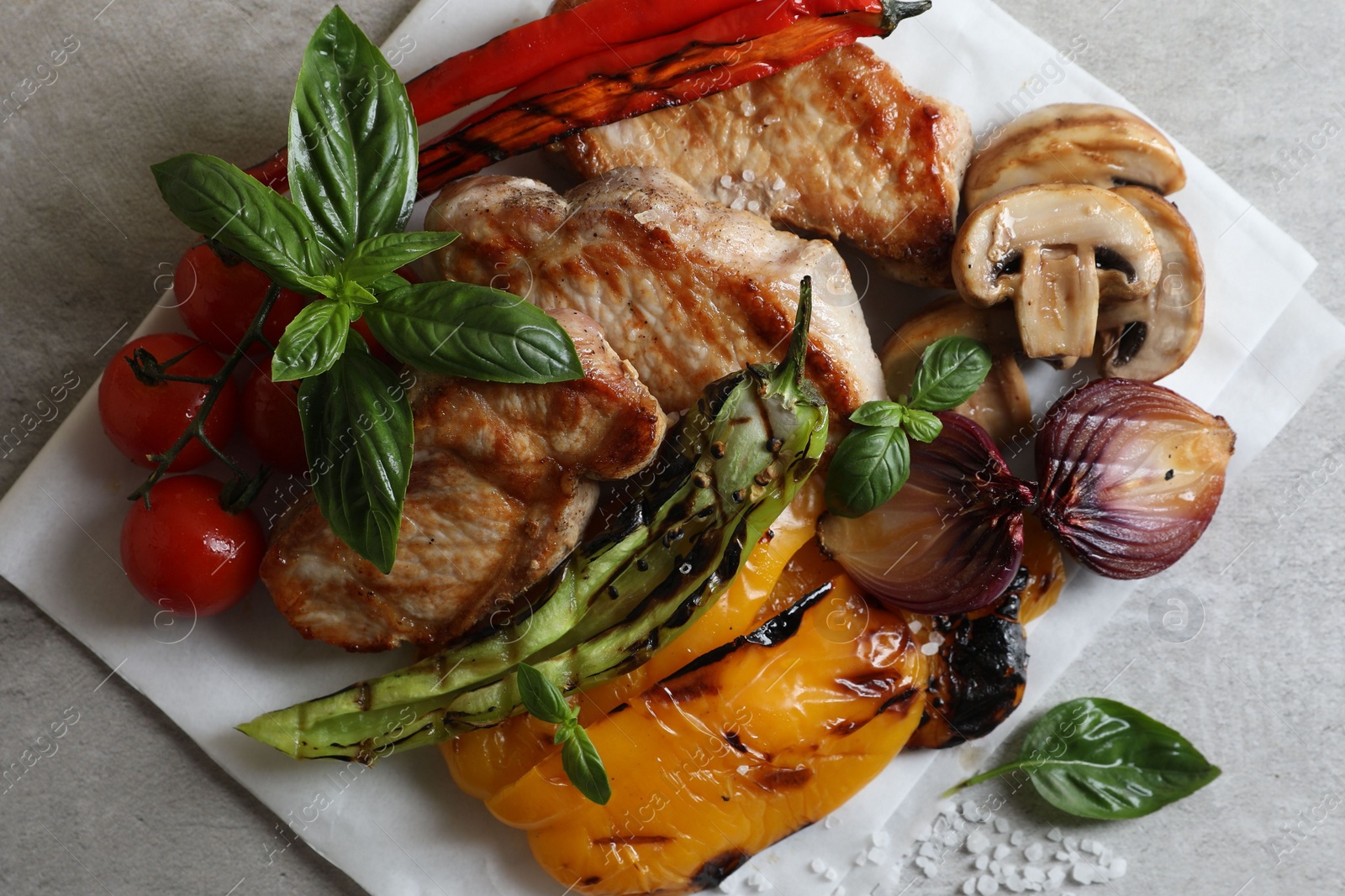 Photo of Tasty grilled meat and vegetables on light grey table, top view