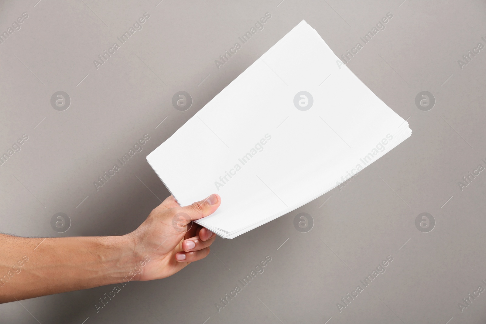 Photo of Man holding sheets of paper on grey background, closeup. Mockup for design