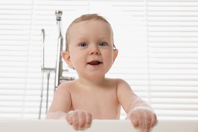 Cute little baby bathing in tub at home