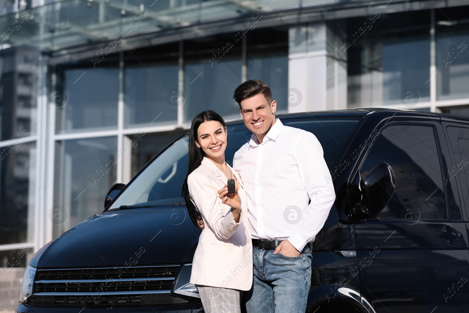 Photo of Happy couple with key near car on city street. Buying new auto