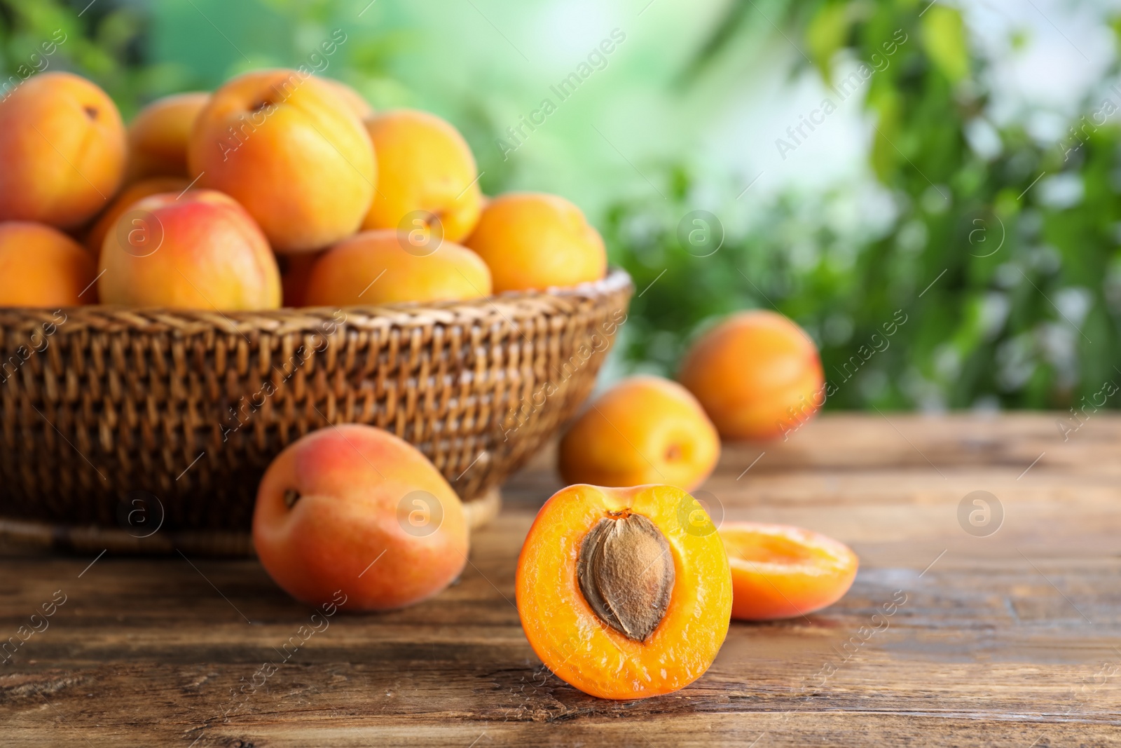 Photo of Many fresh ripe apricots on wooden table against blurred background