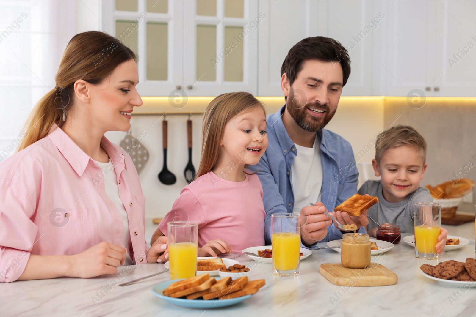 Photo of Happy family having breakfast at table in kitchen